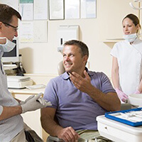 A patient speaking with a dentist and dental assistant