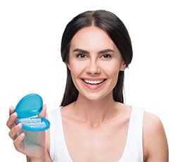 woman holding clear aligner in blue travel case