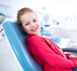 A little girl sitting in the dentist’s chair and smiling waiting for her fluoride treatment