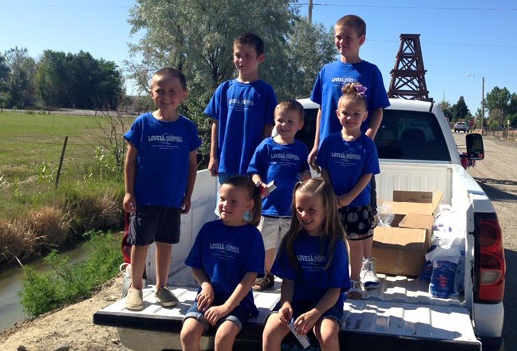 Young kids in back of white truck with Lovell Dental shirts on