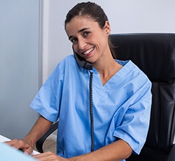 Dental employee smiling while talking on the phone