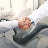 Dentist and patient shaking hands in office