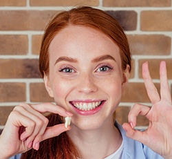 Someone holding a tooth and smiling