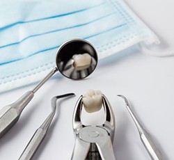 Closeup of dental tools holding and extracted tooth on a white background