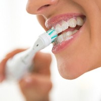 Woman brushing teeth after getting dental implants in Lovell