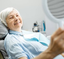 An older woman viewing her smile in a mirror