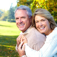 An older couple smiling and hugging outside