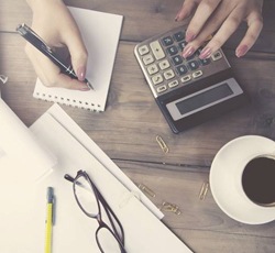 A person holding a pen and using a calculator