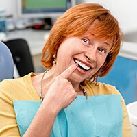 An older woman pointing at her smile