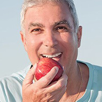 An older man biting into an apple