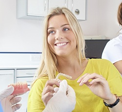 Woman in dental chair holding Invisalign tray