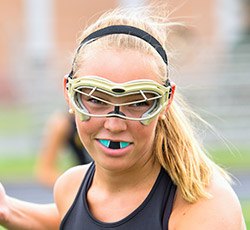 Teen girl playing lacrosse with mouthguard