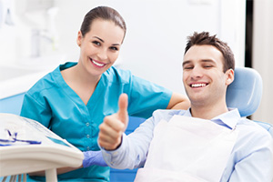 Smiling man in dental chair giving thumbs up