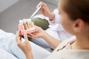 woman holding dental implant during consultation 