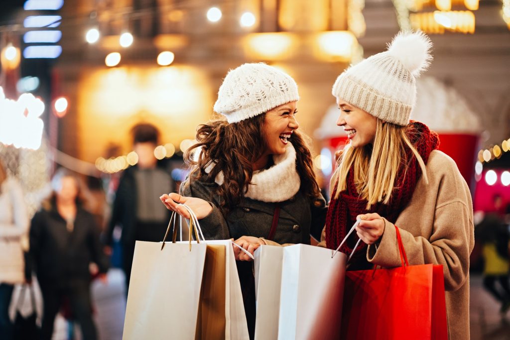 Two women smiling while holiday shopping together